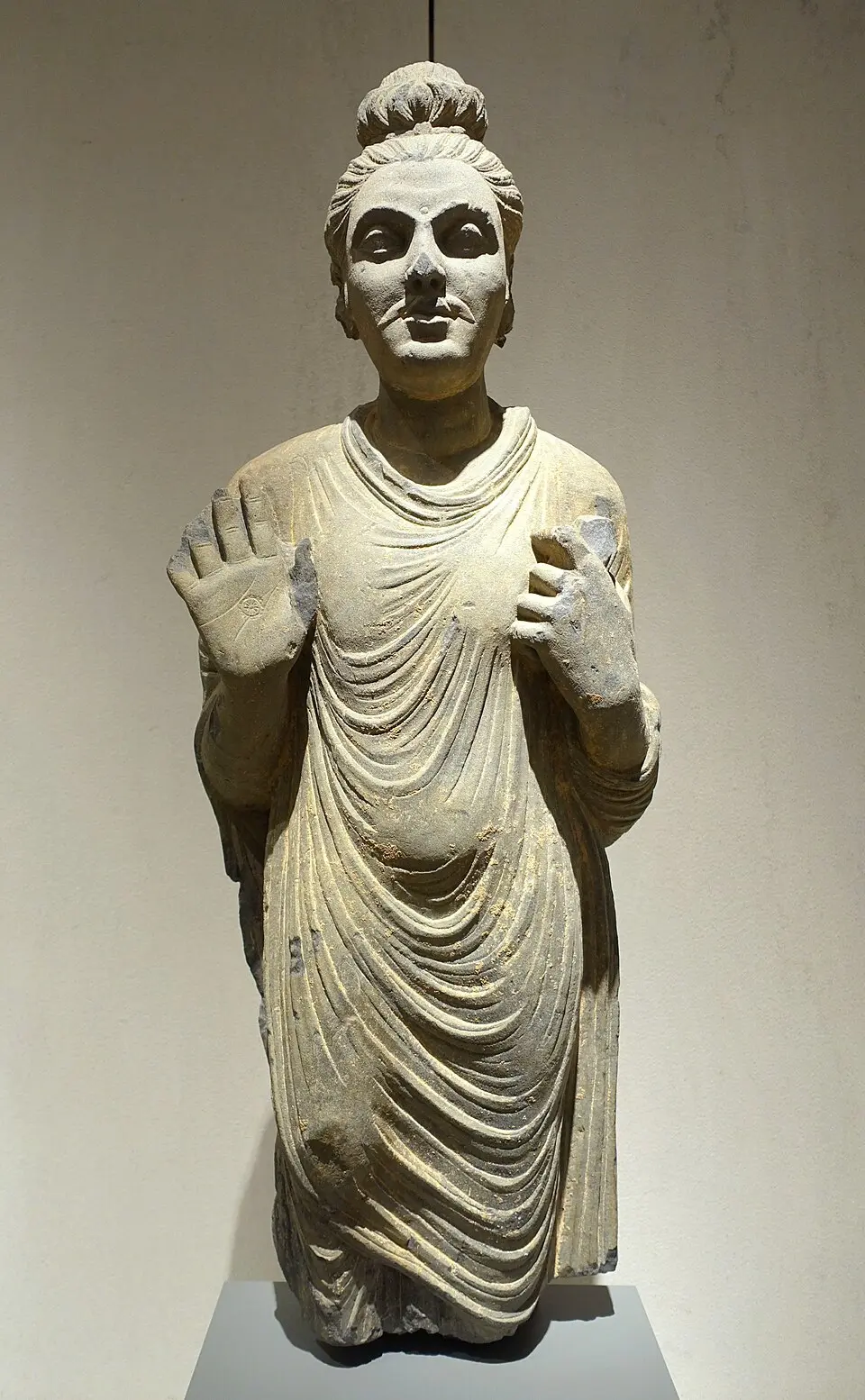 A Gandhara Buddha in grey schist: Hellenistic influence: wavy hair and a toga like robe with heavy naturalistic folds.