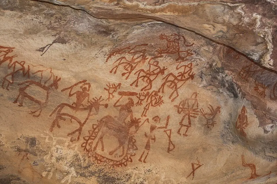 Prehistoric rock painting at Bhimbetka showing human and animal figures in red