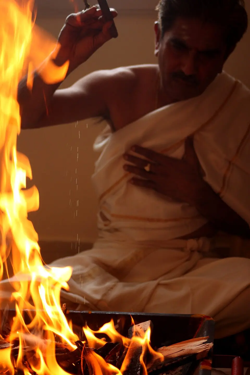 A Brahmin priest making offerings into a homa fire